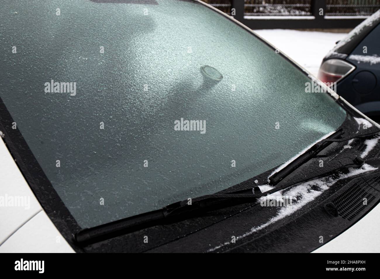 An kalten Wintertagen im Freien bedeckt die Glasscheibe des Autos eine Schicht Eisregen. Konzept für extreme Wetterbedingungen. Stockfoto