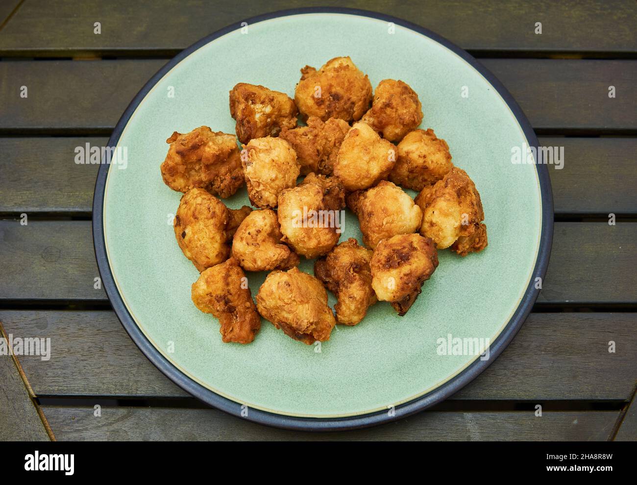 Vegane Blumenkohlbüffelflügel auf weißem Holztisch. Leckeres vegetarisches Essen von oben. Knusprige gebratene Blumenkohlbisse Stockfoto