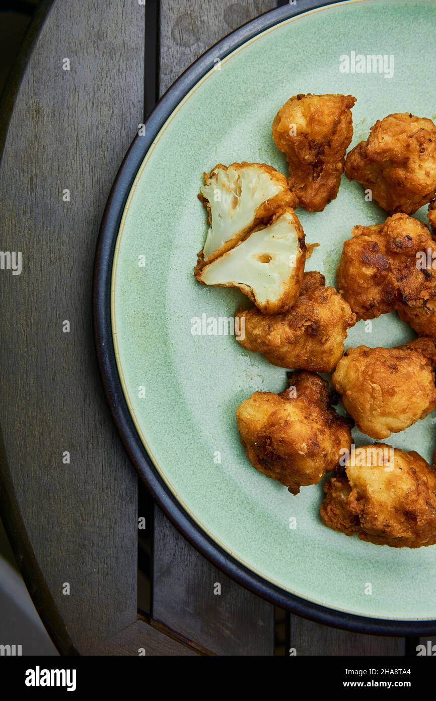 Vegane Blumenkohlbüffelflügel auf weißem Holztisch. Leckeres vegetarisches Essen von oben. Knusprige gebratene Blumenkohlbisse Stockfoto