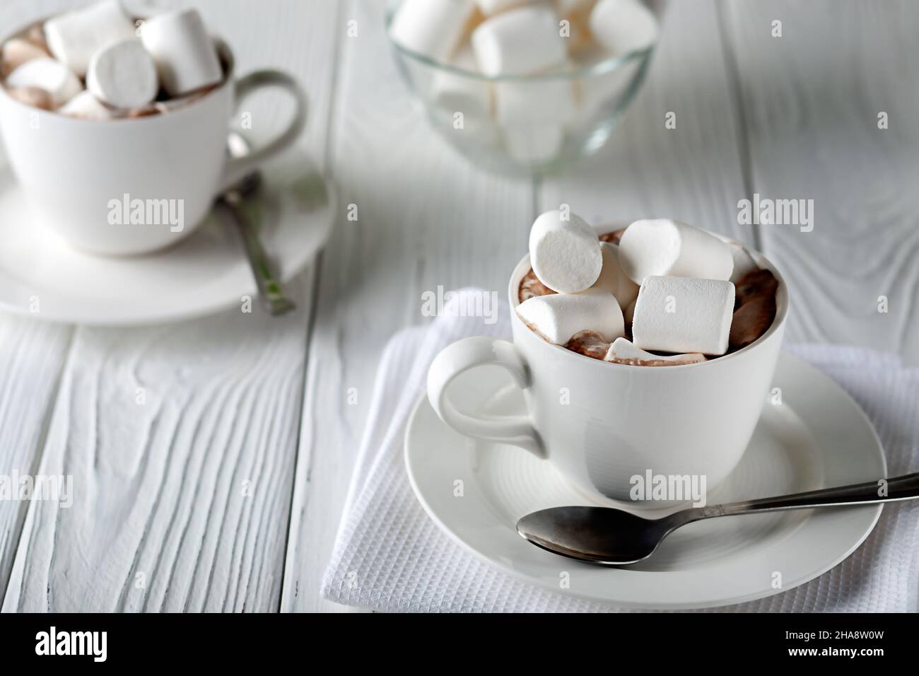 Auf einem weißen Holztisch ein Becher mit heißer Schokolade und Marschwalben Stockfoto