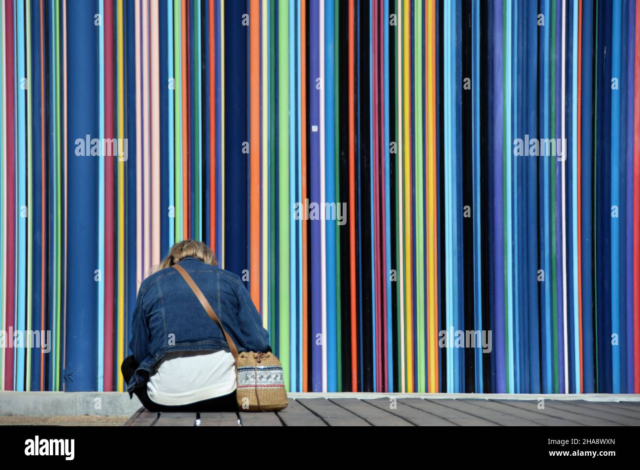Eine Frau, die sich vor einem Kunstwort des Künstlers Raymond Moretti in La Défense, dem Geschäftsviertel von Paris, ausruhte. Das Kunstwerk ist eine Sammlung von riesigen Trinkhalmen Stockfoto