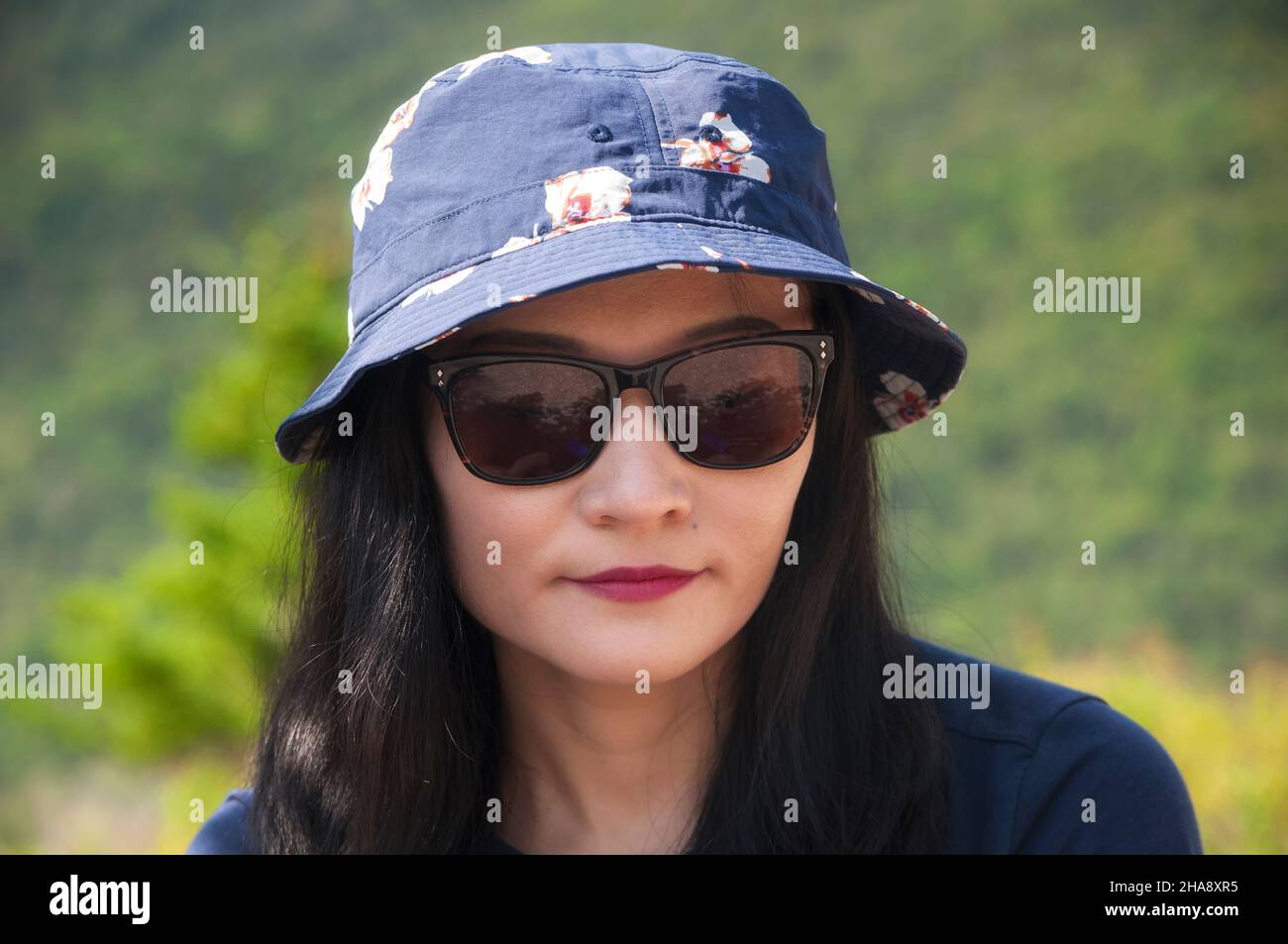 Eine chinesin, die an einem sonnigen Tag in Bretton Woods New Hampshire Sonnenbrille und Hut trägt. Stockfoto