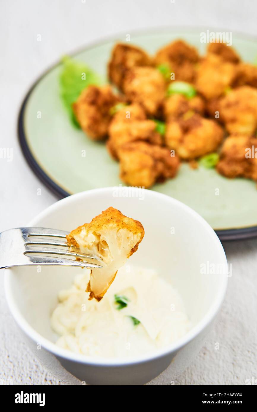 Vegane Blumenkohlbüffelflügel auf einer Gabel. Leckere vegetarische Gerichte aus nächster Nähe. Knusprige gebratene Blumenkohlbse Stockfoto