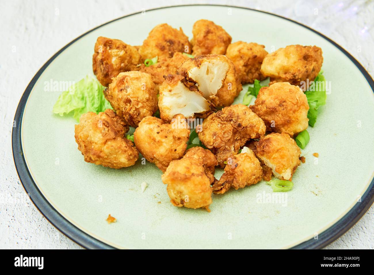 Vegane Blumenkohlbüffelflügel auf weißem Hintergrund.leckeres vegetarisches Essen Draufsicht. Knusprige gebratene Blumenkohlbisse Stockfoto