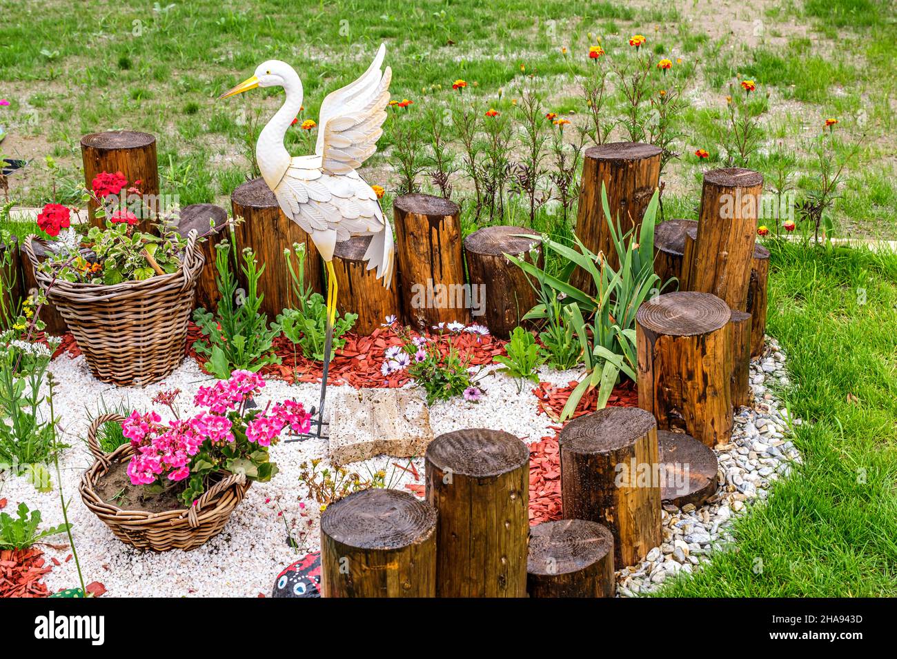 Gartenanlage mit Holzstämmen, Korbkörben, Kies und Ornament in Form von