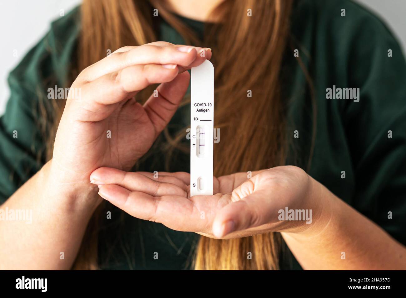 Positives Rapid-Antigen-COVID-19-Testergebnis in Händen einer nicht erkennbaren Person. Frau hält eine schnelle Coronavirus-Antigen-Schnelltestkarte. Positiv getestet auf COVID-19-Konzept. Stockfoto