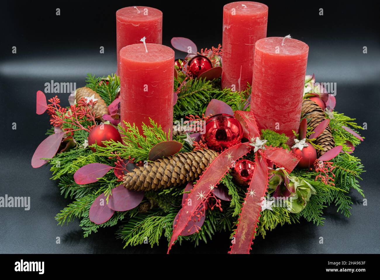 Low-Angle-Ansicht des schönen neuen Adventskranzes mit vier roten Kerzen auf schwarzem Hintergrund. Stockfoto