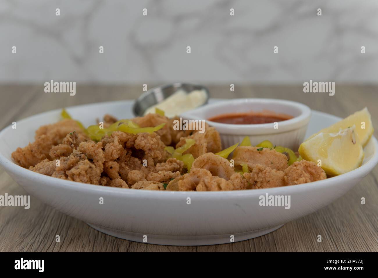 Knusprige Schüssel voller zerschlagener Calamari-Ringe, gemischt mit Paprika, Torte und Cocktailsauce. Stockfoto