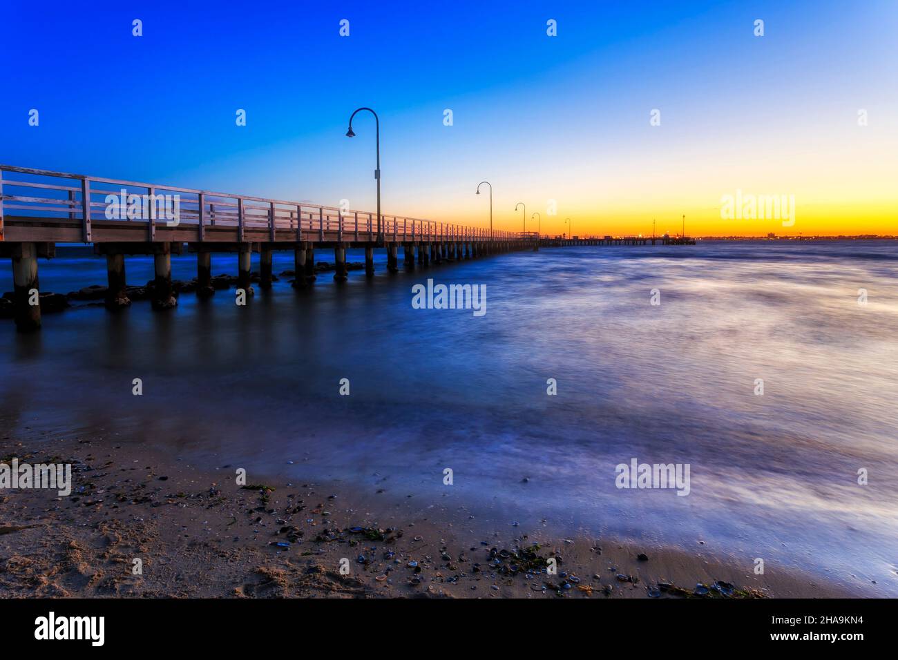 Alter Holzsteg am sandigen Strand von Port Phillip Bay in Melbourne, Australien, bei farbenfrohem Sonnenuntergang. Stockfoto