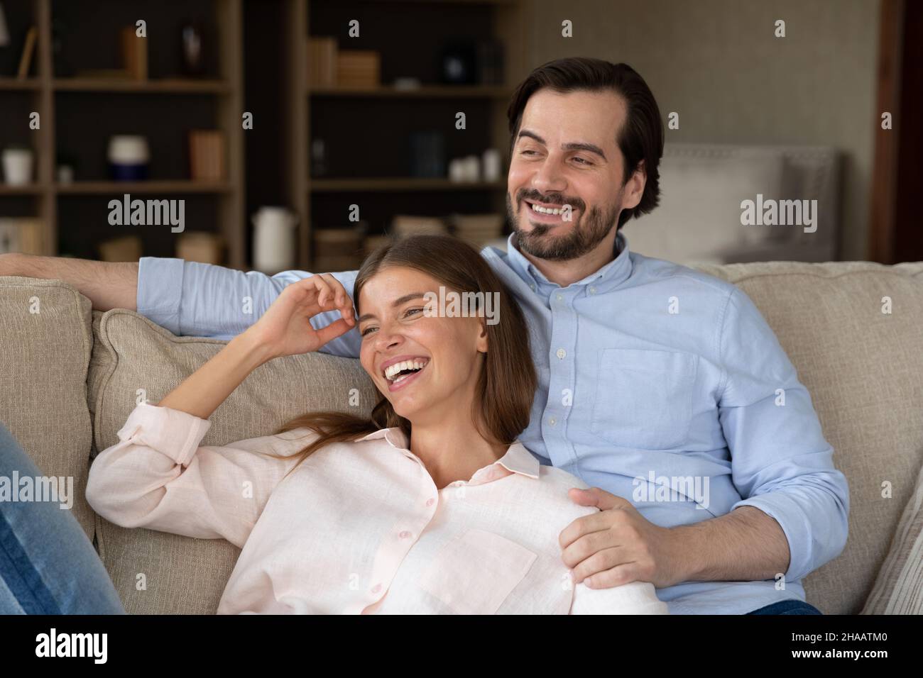 Fröhliches, verträumtes junges Paar, das sich auf dem Sofa ausruhen kann Stockfoto