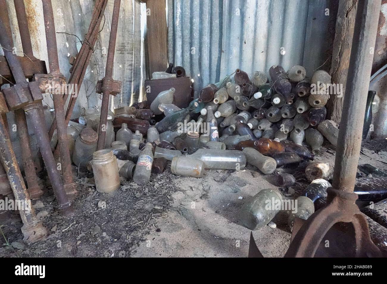 Stapel alter Flaschen in einer Blechhütte Stockfoto