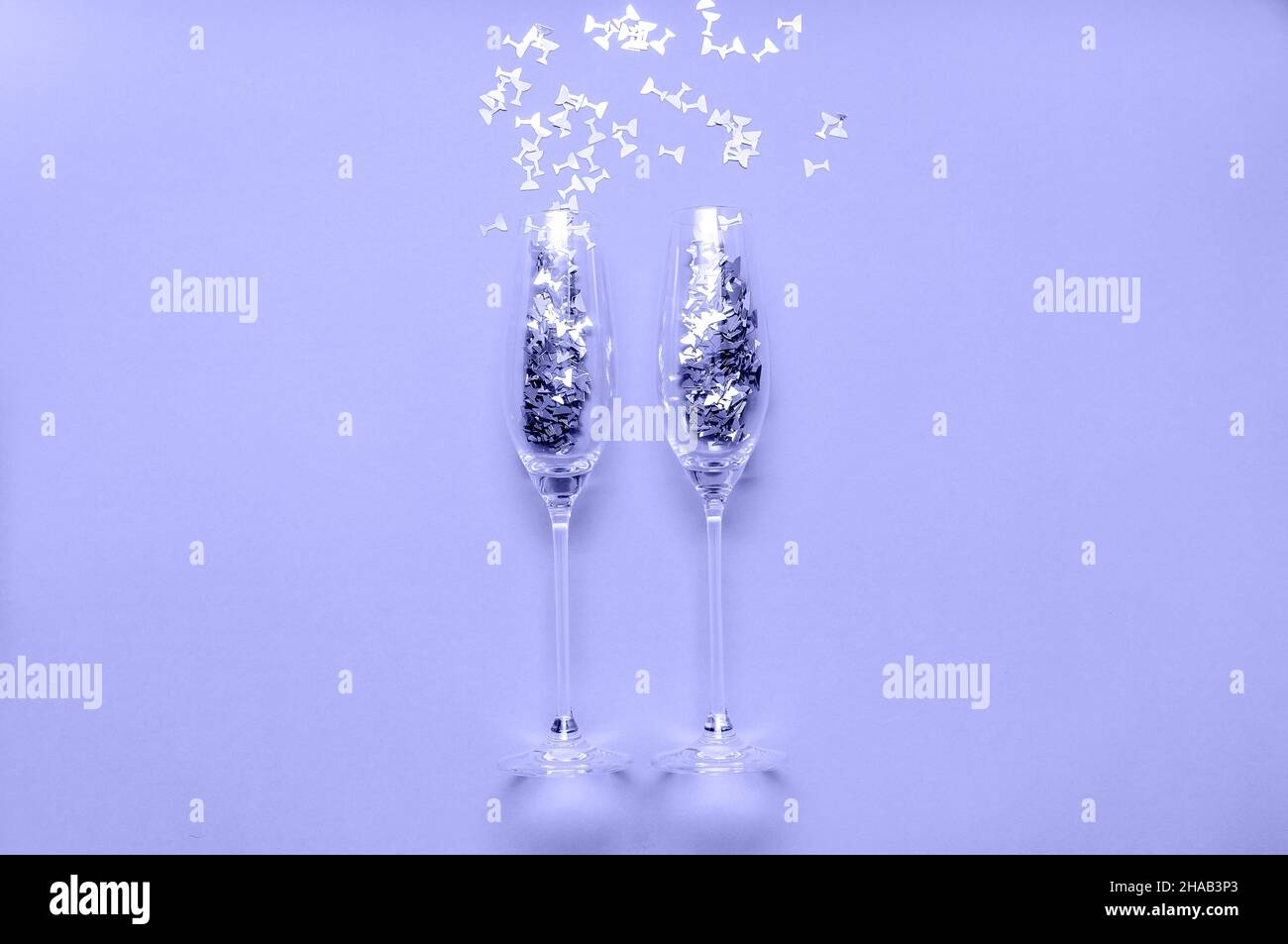 Champagnergläser mit Konfetti in Trendfarbe des Jahres 2022 sehr Peri. Kreatives Weihnachtskonzept Stockfoto