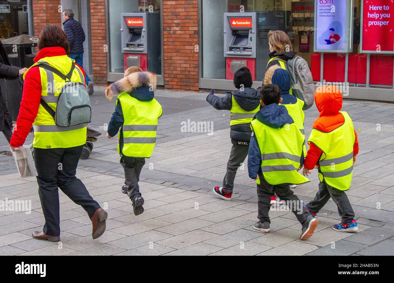 Schutz von Schulkindern mit fluoreszierenden Warnjacken auf einem Spaziergang durch Southport mit Lehrern, Merseyside, Großbritannien Stockfoto