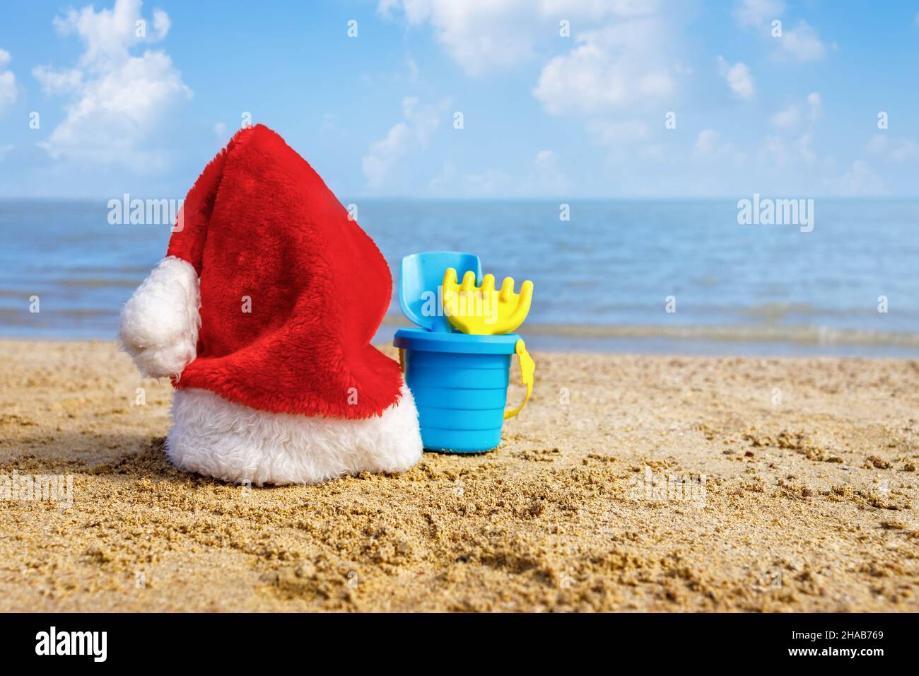 weihnachtsmütze und Set von Plastikspielzeug für Kinder auf Sand in der Nähe des Meeres Stockfoto