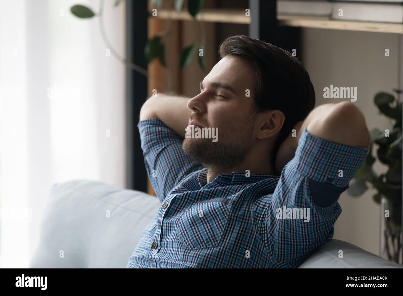 Mann entspannt auf Sofa Tagträume Genießen Sie das Wochenende im modernen Zuhause Stockfoto