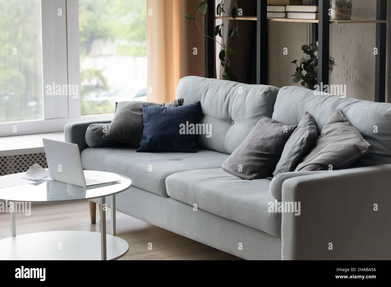 Wohnzimmer mit grauem Sofa und Laptop auf Couchtisch Stockfoto
