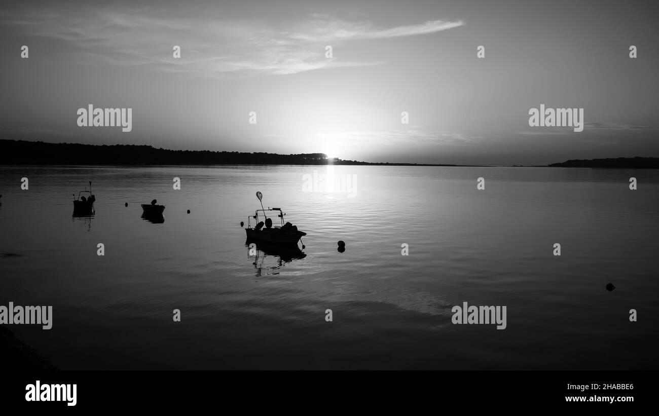 Silhouetten von Fischerbooten auf dem Minho River bei Sonnenuntergang. Schwarzweiß-Foto. Stockfoto