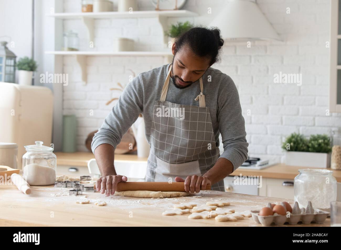 Afrikanischer Mann rollt den Teig für die Zubereitung von Keksen aus Stockfoto