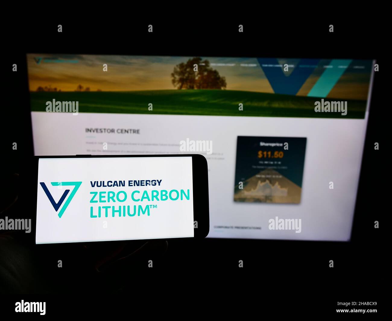 Person, die Mobiltelefon mit dem Logo des australischen Unternehmens Vulcan Energy Resources Ltd auf dem Bildschirm vor der Business-Webseite hält. Konzentrieren Sie sich auf die Telefonanzeige. Stockfoto