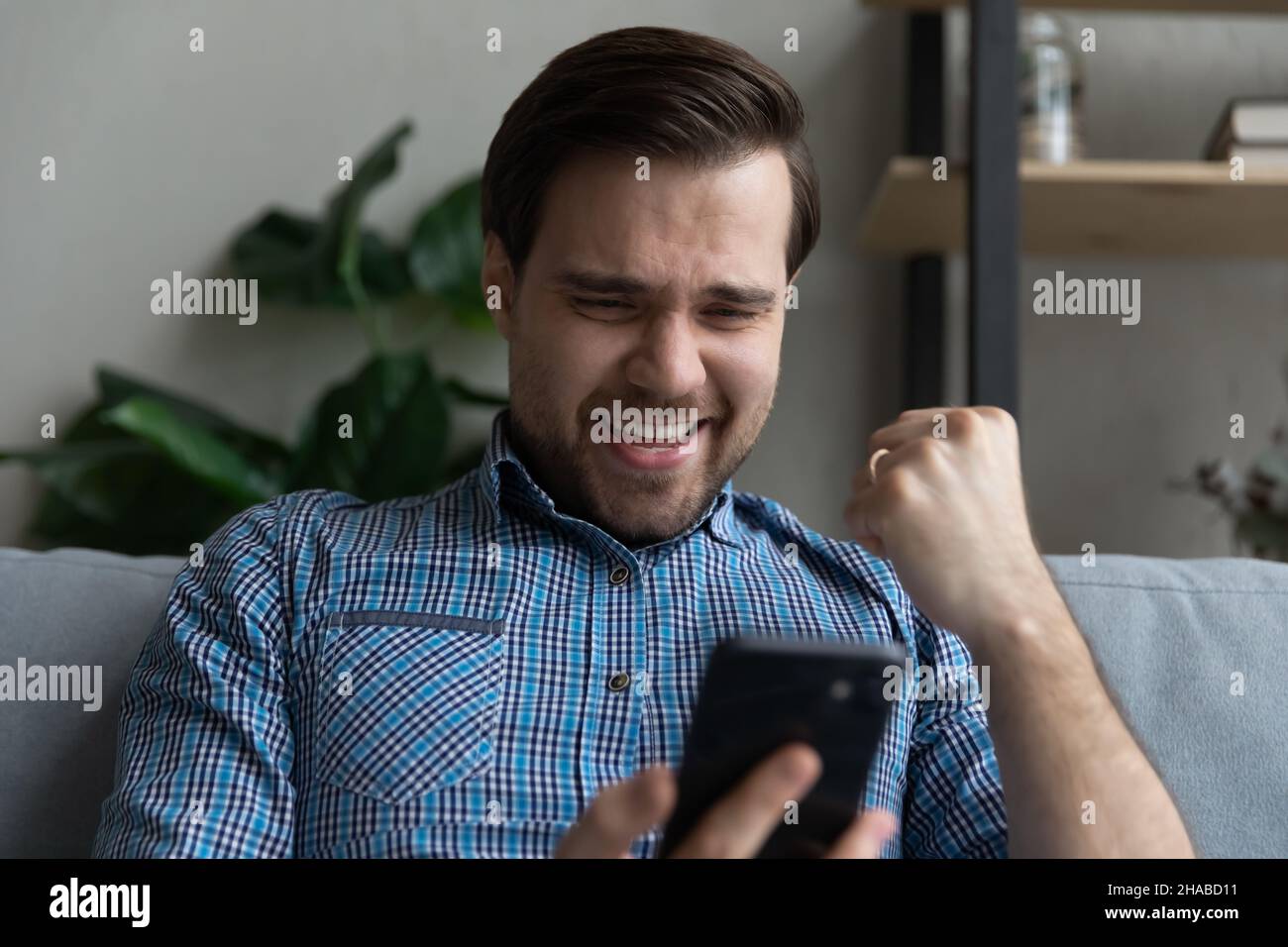 Mann schaut auf Handy-Bildschirm fühlt sich überglücklich bekam gute Nachrichten Stockfoto