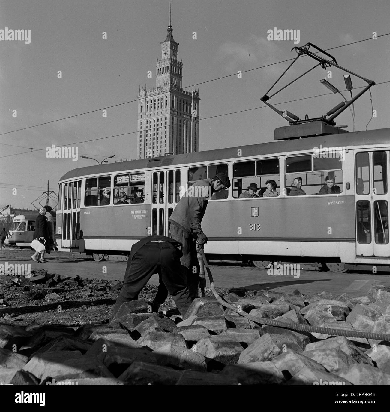 Warszawa, 1969-10. Przebudowa skrzy¿owania ulicy Marsza³kowskiej z Alejami Jerozolimskimi, jednego z najwiêkszych warszawskich skrzy¿owañ. NZ. Robotnicy usuwaj¹ star¹ nawierzchniê z jezdni. W tle tramwaj nr 25 - jedzie Alejami Jerozolimskimi w stronê Mostu Poniatowskiego - oraz Pa³ac Kultury i Nauki (PKiN). Ad PAP/Adam Urbanek Dok³adny dzieñ wydarzenia nieustalony. Warschau, Oktober 1969. Wiederaufbau der Kreuzung der Straßen Marszalkowska und Jerozolimskie, einer der größten Kreuzungen in Warschau. Im Bild: Arbeiter entfernen den alten Pflaster. Im Hintergrund Straßenbahn Nr. 25 - entlang fahren Stockfoto