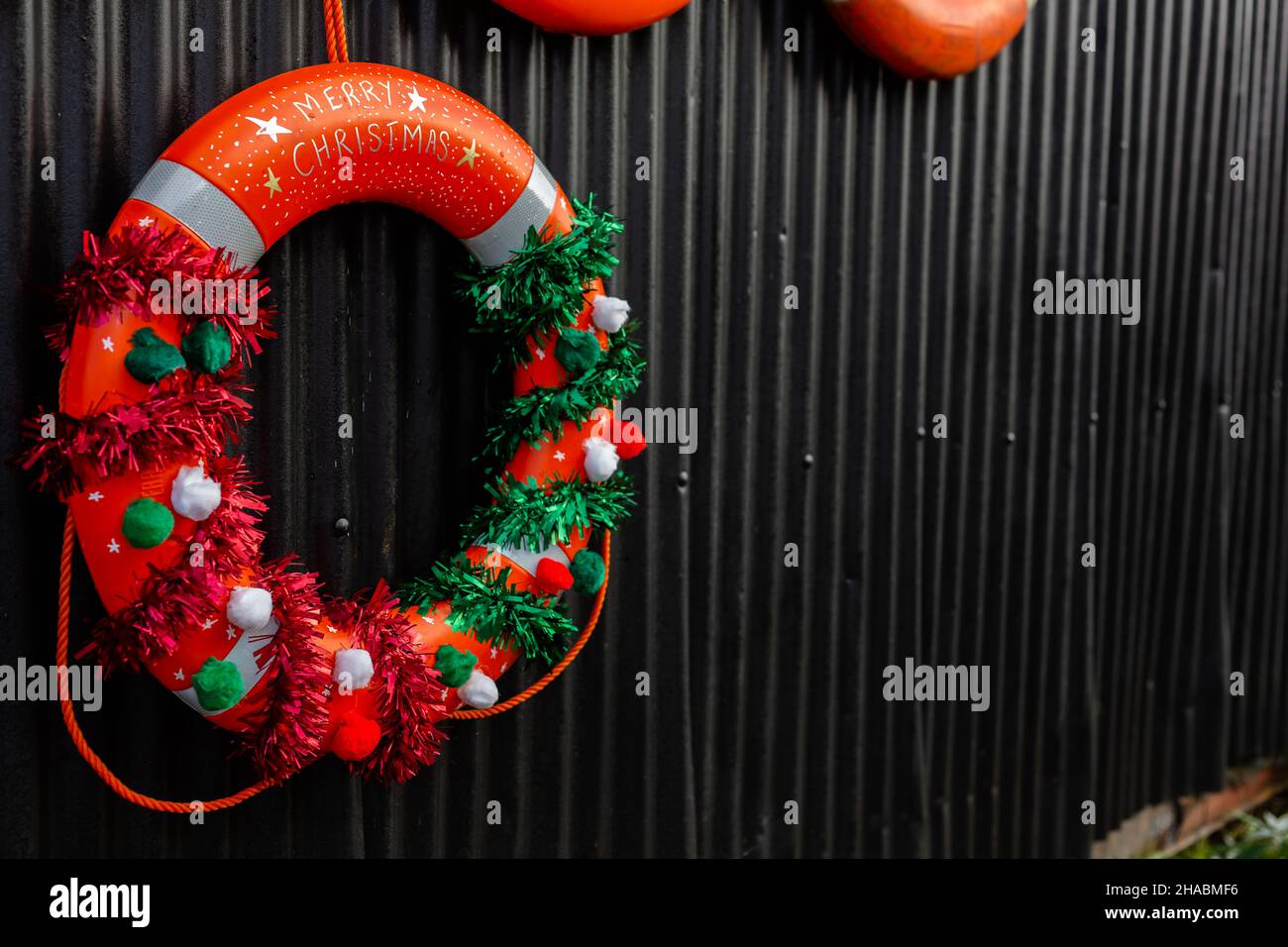 Ein Weihnachtskranz aus einer Rettungsboje, der in der Öffentlichkeit vor einem Segelclub aufhängt Stockfoto