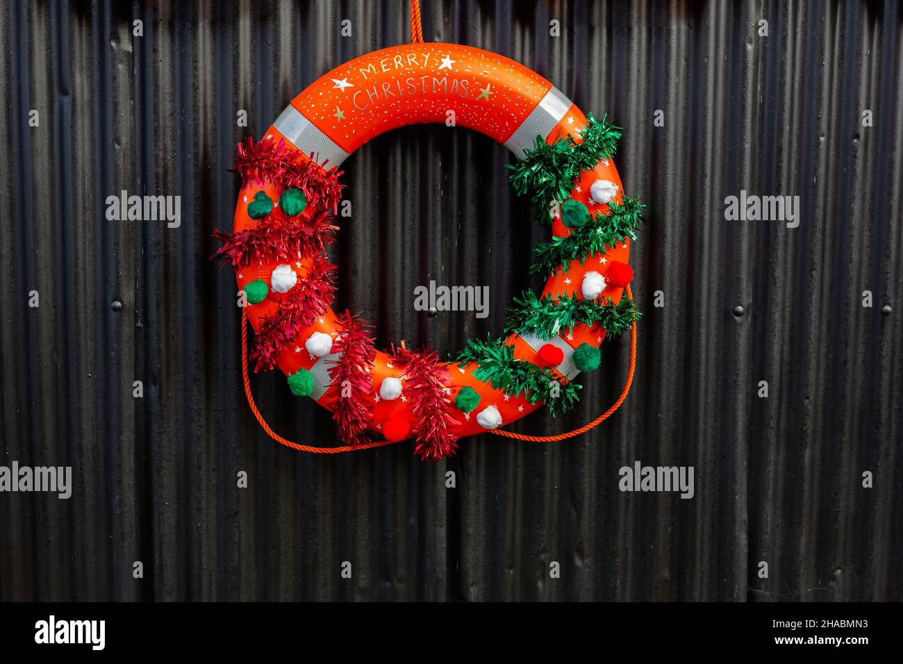 Ein Weihnachtskranz aus einer Rettungsboje, der in der Öffentlichkeit vor einem Segelclub aufhängt Stockfoto