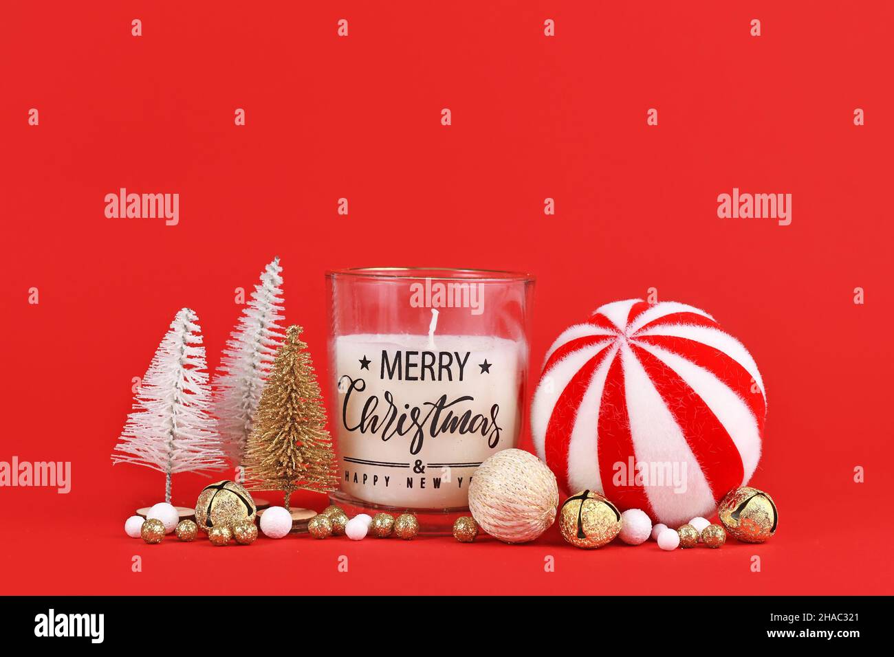 Weihnachtsarrangement mit goldenen und weißen Bäumen, Kerze und Kugeln auf rotem Hintergrund mit Kopierraum Stockfoto