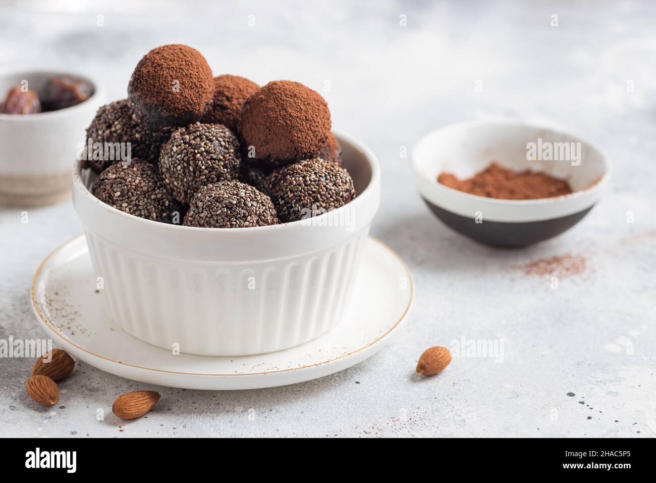 Rohe Energiekugeln mit Chiasamen, Kakaopulver auf grauem Hintergrund Stockfoto