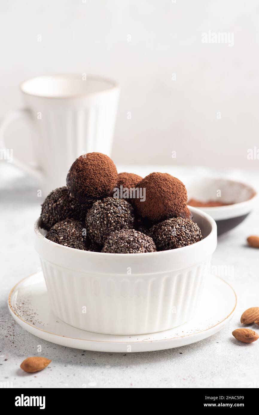 Rohe Energiekugeln aus Datteln, Nüssen, Chiasamen in weißer Schale Stockfoto