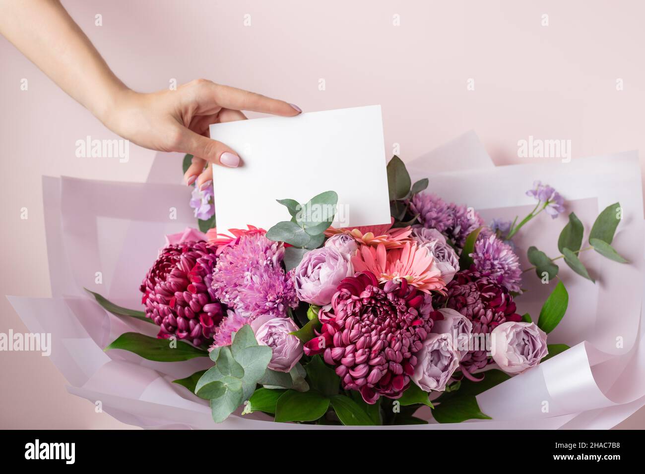 Blumenhändler Hand Lege leere Papierkarte auf schönen Blumenstrauß Stockfoto