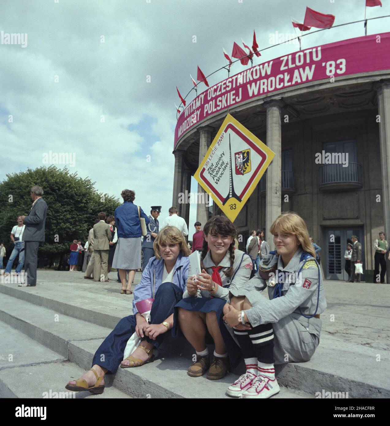 Wroc³aw 20.07.1983. Ogólnokrajowy Zlot M³odzie¿y Polskiej (w dniach 19-20.07.1983) z okazji 35. Rocznicy zjednoczenia ruchu m³odzie¿owego i powo³ania Zwi¹zku M³odzie¿y Polskiej. W uroczystoœciach udzia³ wziêli dzia³acze organizacji m³odzie¿owych oraz uczestnicy kongresu zjednoczeniowego z 1948 roku. NZ. Uczestnicy zjazdu przed gmachem Hali Ludowej. wb PAP/Jan Morek Breslau, Den 20. Juli 1983. Die gesamtpolnische Jugendversammlung (19. Bis 20. Juli 1983) anlässlich des 35th. Jahrestages der Vereinigung der Jugendbewegung und der Gründung der Polnischen Jugendunion. Die Zeremonien wurden besucht Stockfoto