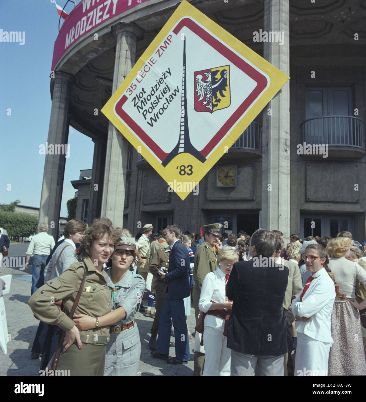 Wroc³aw 20.07.1983. Ogólnokrajowy Zlot M³odzie¿y Polskiej (w dniach 19-20.07.1983) z okazji 35. Rocznicy zjednoczenia ruchu m³odzie¿owego i powo³ania Zwi¹zku M³odzie¿y Polskiej. W uroczystoœciach udzia³ wziêli dzia³acze organizacji m³odzie¿owych oraz uczestnicy kongresu zjednoczeniowego z 1948 roku. NZ. Uczestnicy zjazdu przed gmachem Hali Ludowej. wb PAP/Jan Morek Breslau, Den 20. Juli 1983. Die gesamtpolnische Jugendversammlung (19. Bis 20. Juli 1983) anlässlich des 35th. Jahrestages der Vereinigung der Jugendbewegung und der Gründung der Polnischen Jugendunion. Die Zeremonien wurden besucht Stockfoto