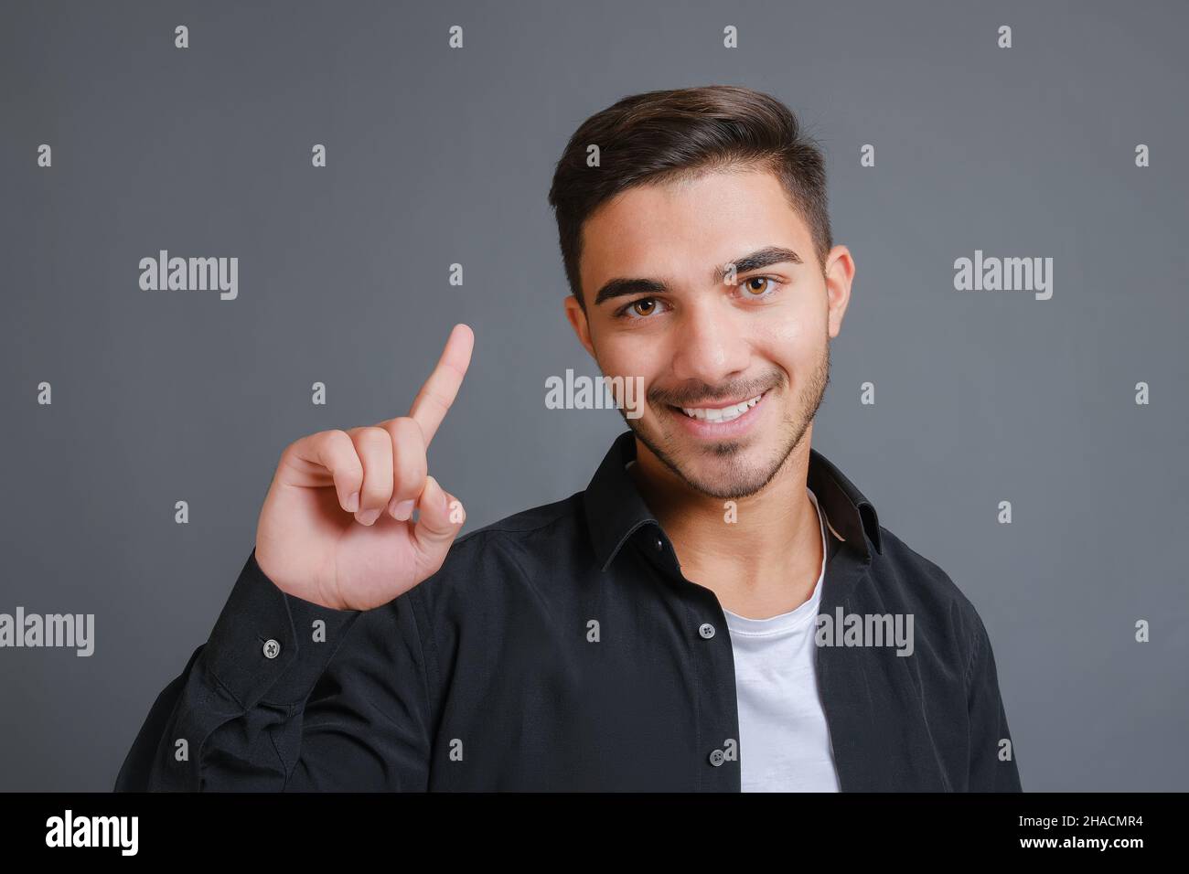 Mann im schwarzen Hemd zeigt seinen Zeigefinger nach oben Stockfoto