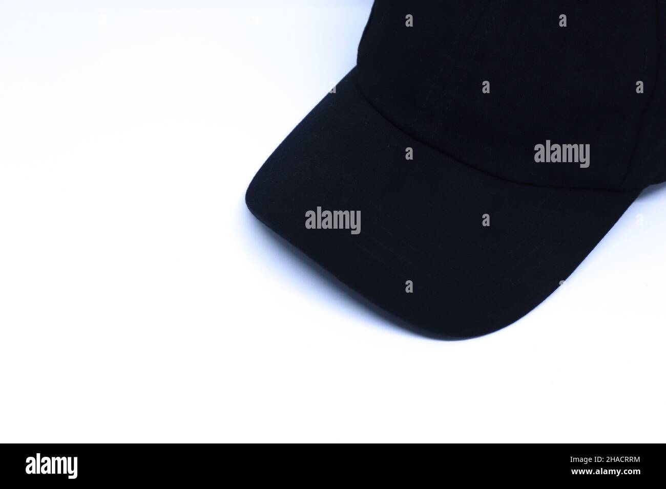 Ein schwarzer Hut in der Ecke des minimalistischen weißen Hintergrunds mit schrägem Top Shot, Landschaftsmodus Stockfoto