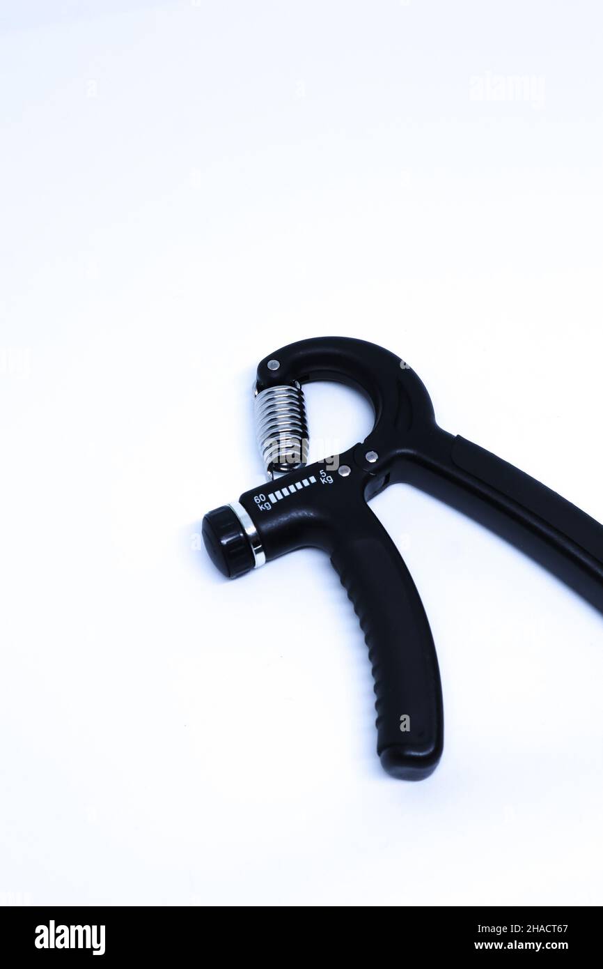 Oblique Top Shot eines Black Hand Grip Exercise Tools im minimalistischen weißen Hintergrund im Portrait-Modus Stockfoto