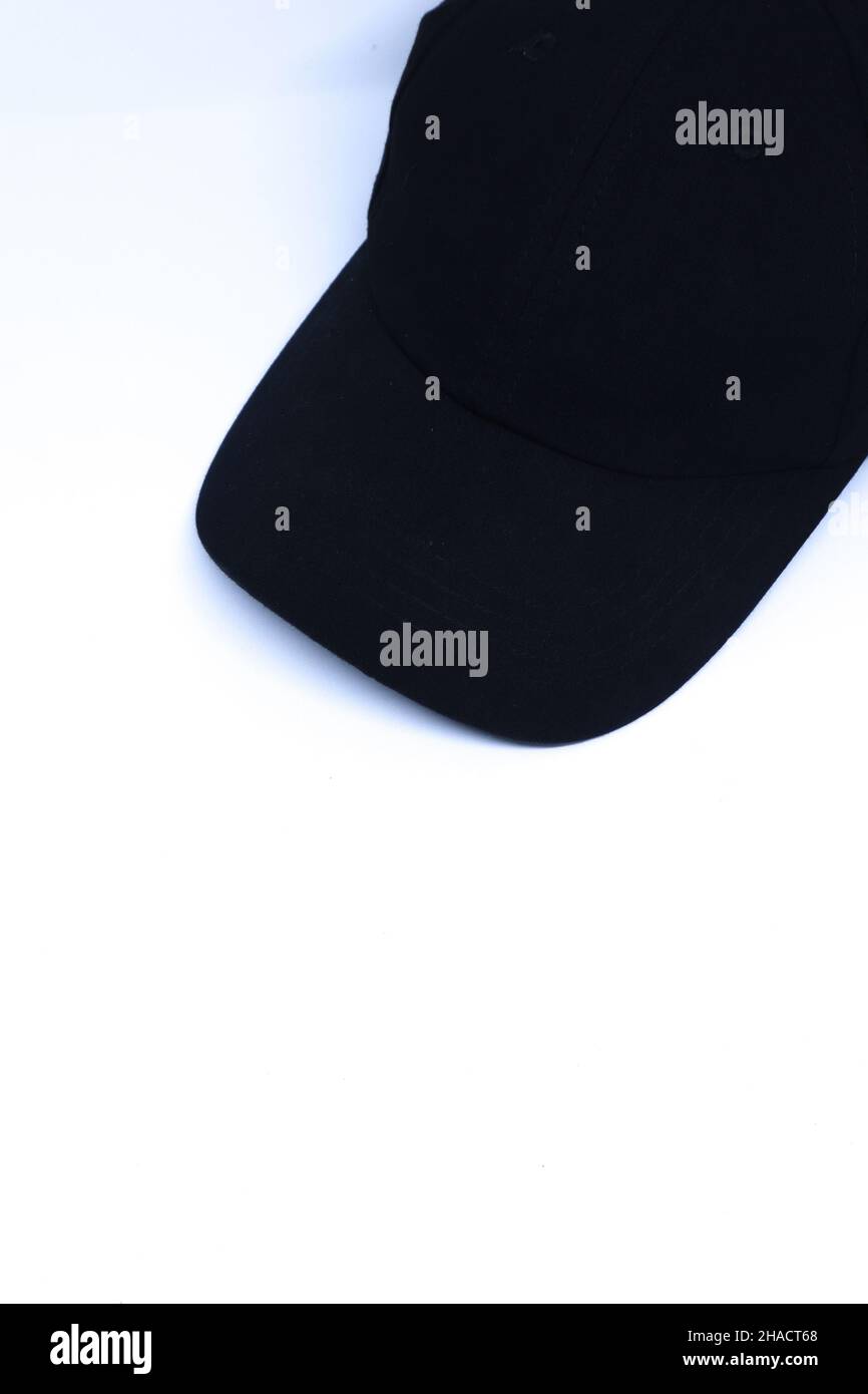 Schräge Aufnahme Einer schwarzen Mütze in der Ecke eines minimalistisch-weißen Hintergrunds, Portrait-Modus Stockfoto