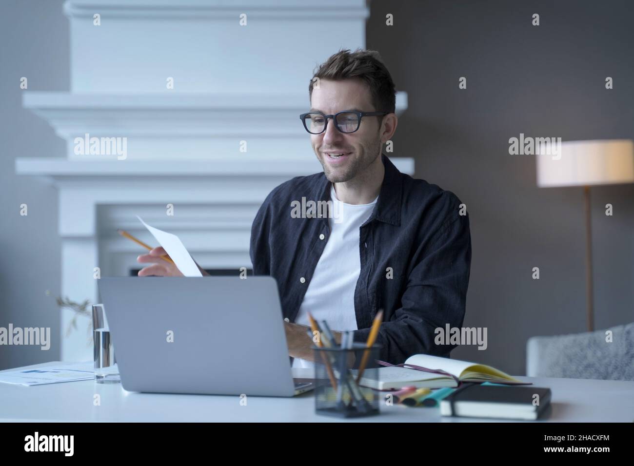 Junger, verfeinerter männlicher Unternehmer mit Brille spricht während einer Webkonferenz über das Internet Stockfoto