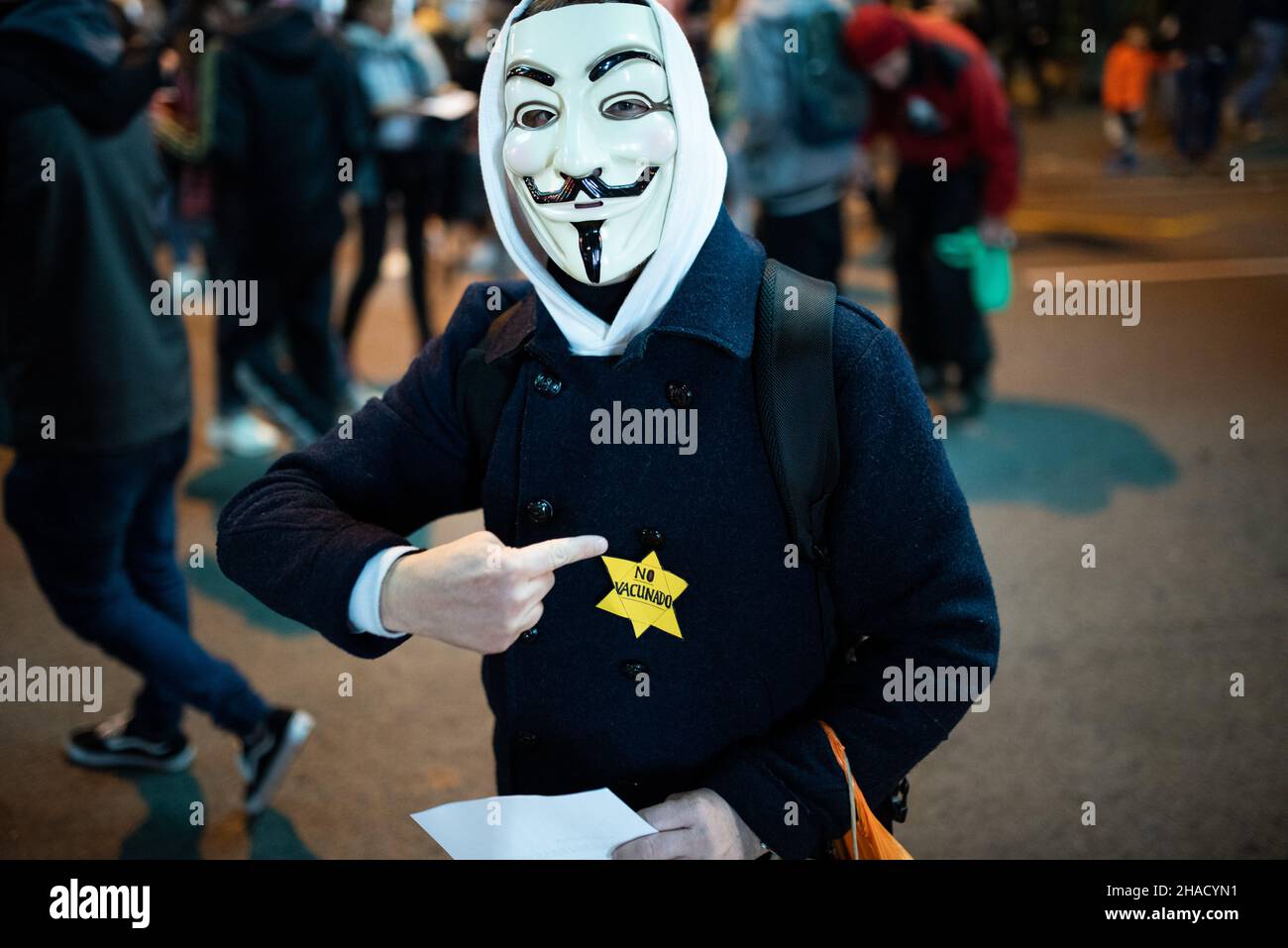 Spanien. 11th Dez 2021. Ein Mann trägt einen gelben Stern, bekannt als jüdisches Abzeichen, und liest „nicht geimpft“ und eine Vendetta-Maske während einer Demonstration der Antivaxbewegung gegen die Covid-Impfstoffe und den Covid-Impfpass, bekannt als Green Pass, im Stadtzentrum von Barcelona in Spanien am 11. Dezember 2021. Der Covid-19-Pass ist für den Zugang zu Bars und Restaurants in Katalonien und anderen Regionen Spaniens bekannt. (Foto von Davide Bonaldo/Sipa USA) Quelle: SIPA USA/Alamy Live News Stockfoto