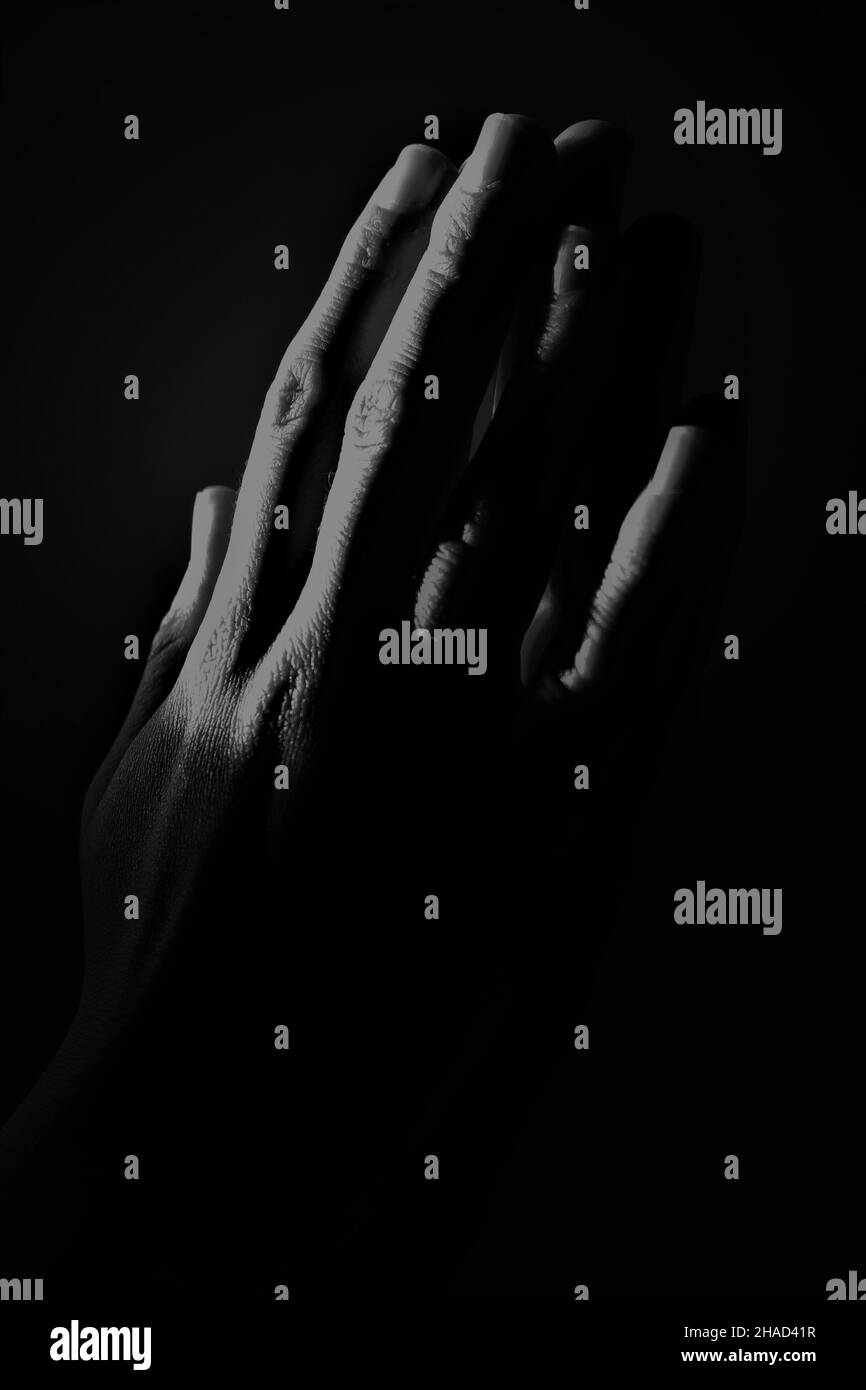 Abstrakte Hände in krassem Schwarz und Weiß zusammengedrückt, wobei nur die Finger hervorgehoben sind Stockfoto