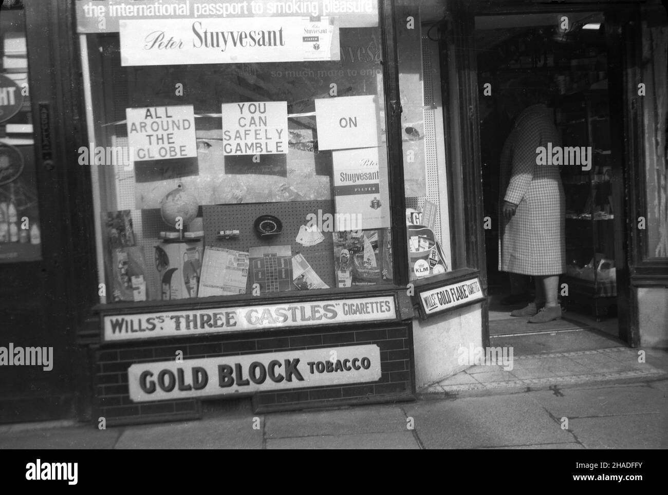 1958, Außenansicht des Schaufensters eines Tabakwarenhandels, John Isaacs, Half Moon Street, Sherborne, Dorset, England, Großbritannien. John Isaacs war ursprünglich Friseur und die Räumlichkeiten zu einer Zeit, kombiniert mit dem Verkauf von Tabak. Im Fenster, Werbung für Peter Stuyvesant Zigaretten, "der internationale Pass zum Rauchvergnügen" und "rund um den Globus, können Sie sicher auf Peter Stuyvesant spielen." Die Marke wurde ‘in Deutschland gegründet und mit ihrer „amerikanischen Mischung“ aus Tabak aus verschiedenen Ländern als international propagiert. Gezeigt wurden auch Wills Three Castles Cigarettes & Gold Block Tabak. Stockfoto 1958, Außenansicht des Schaufensters eines Tabakwarenhandels, John Isaacs, Half Moon Street, Sherborne, Dorset, England, Großbritannien. John Isaacs war ursprünglich Friseur und die Räumlichkeiten zu einer Zeit, kombiniert mit dem Verkauf von Tabak. Im Fenster, Werbung für Peter Stuyvesant Zigaretten, "der internationale Pass zum Rauchvergnügen" und "rund um den Globus, können Sie sicher auf Peter Stuyvesant spielen." Die Marke wurde ‘in Deutschland gegründet und mit ihrer „amerikanischen Mischung“ aus Tabak aus verschiedenen Ländern als international propagiert. Gezeigt wurden auch Wills Three Castles Cigarettes & Gold Block Tabak. Stockfoto