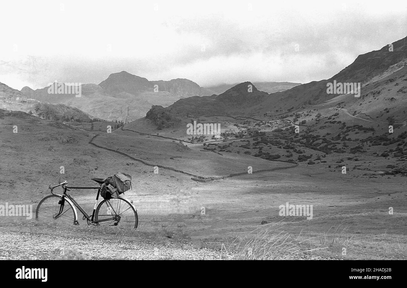 1960s, historisch, ein Tourenrad der Zeit, mit Sitztasche oder Fahrradtasche, geparkt an der Seite einer Landpipe, mit Blick auf die umliegende hügelige englische Landschaft aus Tälern und Hügeln, England, Großbritannien. Stockfoto