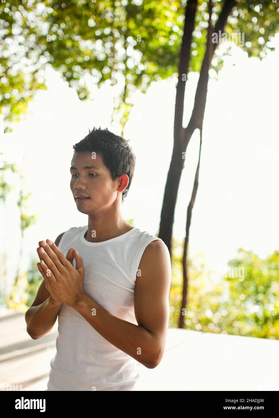 Ein Mann, der im Six Senses Hideaway Yao Noi, Koh Yao Noi, Thailand, Yoga im Freien praktiziert. Ein Yogalehrer gibt einen privaten Yoga-Kurs auf der Baumwipfel pla Stockfoto