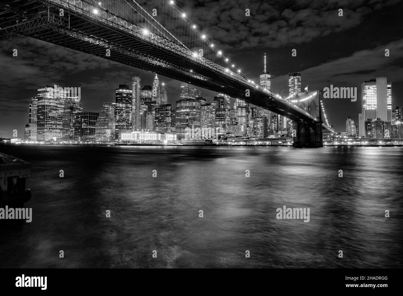 Der East River fließt unter der Brooklyn Bridge mit der Skyline von Manhattan im Hintergrund Stockfoto