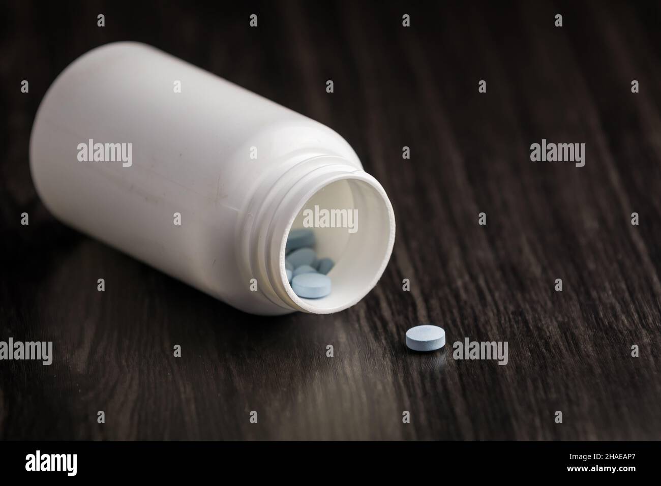 Medikationspille in einer Reihe vor einem Holzhintergrund. Weiße Pillenflasche Stockfoto