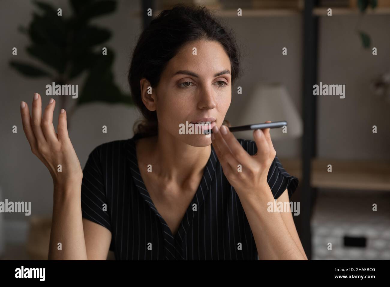 Hispanische Frau zeichnet Sprachnachrichten auf dem Smartphone auf Stockfoto