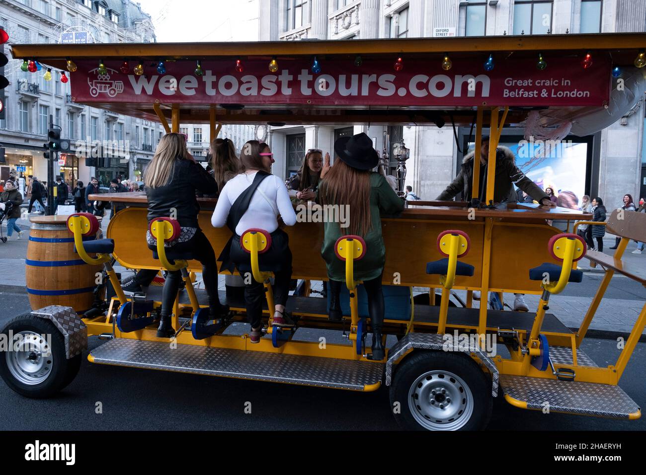 Eine Gruppe von Frauen, die am 22nd. November 2021 in London, Großbritannien, einen Radweg durch die Stadt auf einer gemieteten Wee Toast Tours Fahrradbar genießen, um einen 21st. Geburtstag in der Oxford Street zu feiern. Diese mobilen Barführungen mit mehreren Sitzplätzen sind eine unterhaltsame Möglichkeit für Gruppen, die Sehenswürdigkeiten zu genießen, während sie feiern und einen Drink zu sich nehmen. Oft für Geburtstage, Junggesellenabschiede oder Junggesellinnenabschiede usw. Stockfoto