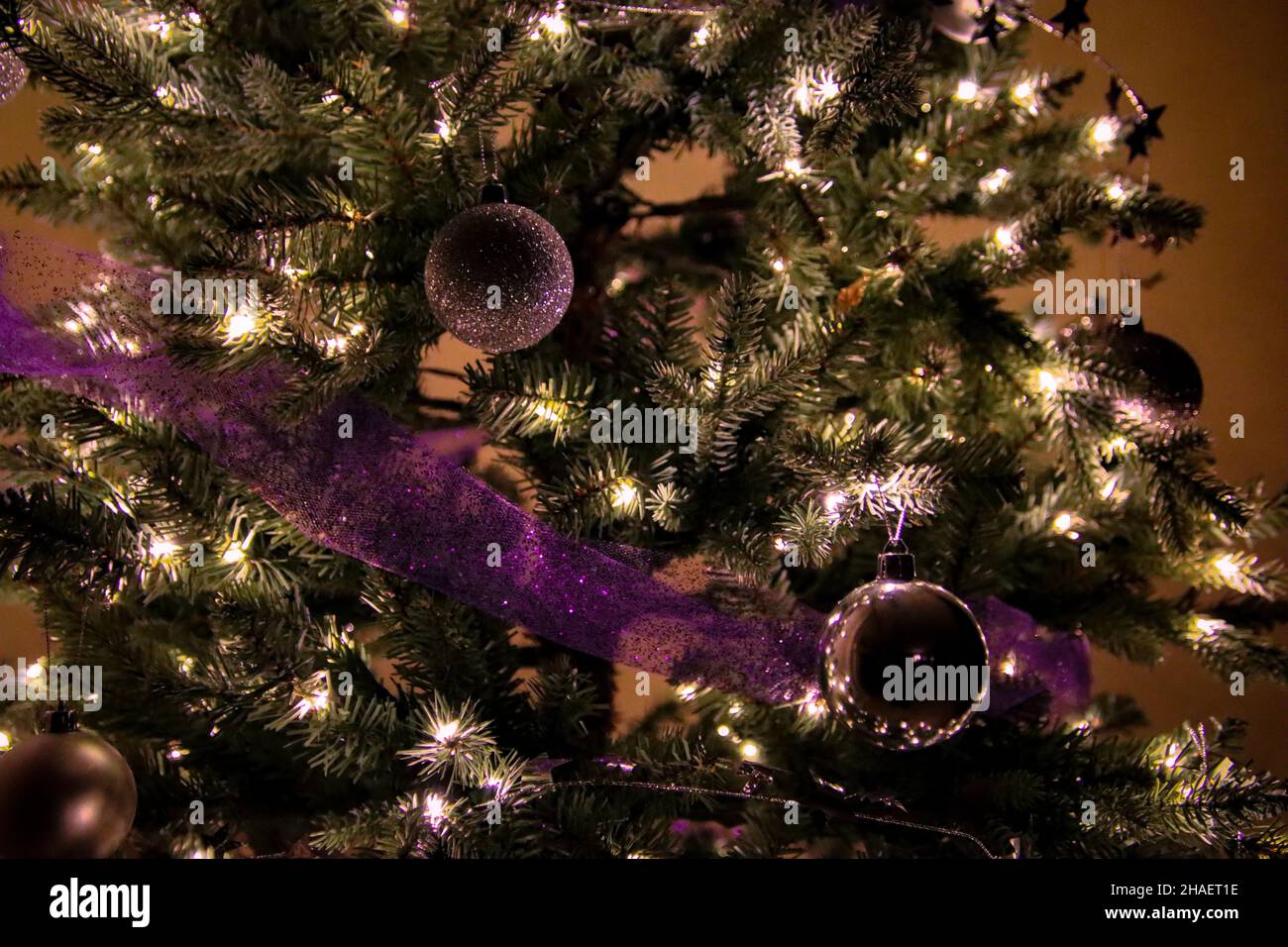 Nahaufnahme von dekorierten Weihnachtsbaum, silbernen Ornamentkugeln und lila glitzernden Band Girlande Stockfoto