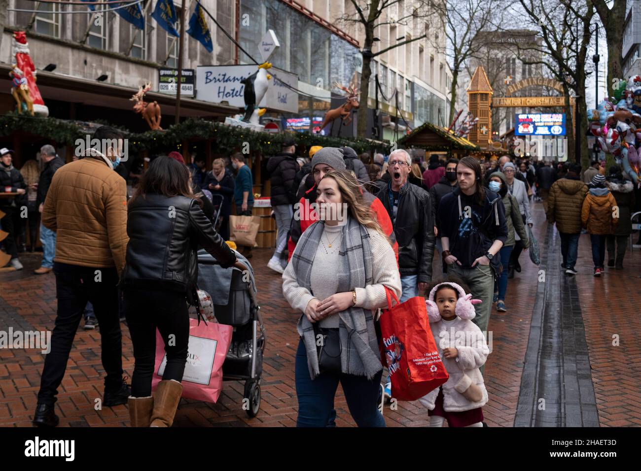 Massen von Weihnachtseinkäufern, einige mit Gesichtsmasken und andere nicht, kommen zum Bull Ring Shopping Centre, da die Entstehung der neuen Covid-19 Omicron-Variante am 12th. Dezember 2021 in Birmingham, Großbritannien, fortgesetzt wird. Die Beschränkungen sind vor etwa 2 Wochen gestiegen, wodurch Gesichtsbedeckungen in Geschäften und öffentlichen Verkehrsmitteln obligatorisch werden. Trotz der neuen Regeln trägt die Mehrheit der Menschen weder draußen in überfüllten Einkaufsvierteln noch im Einkaufszentrum Masken. Stockfoto