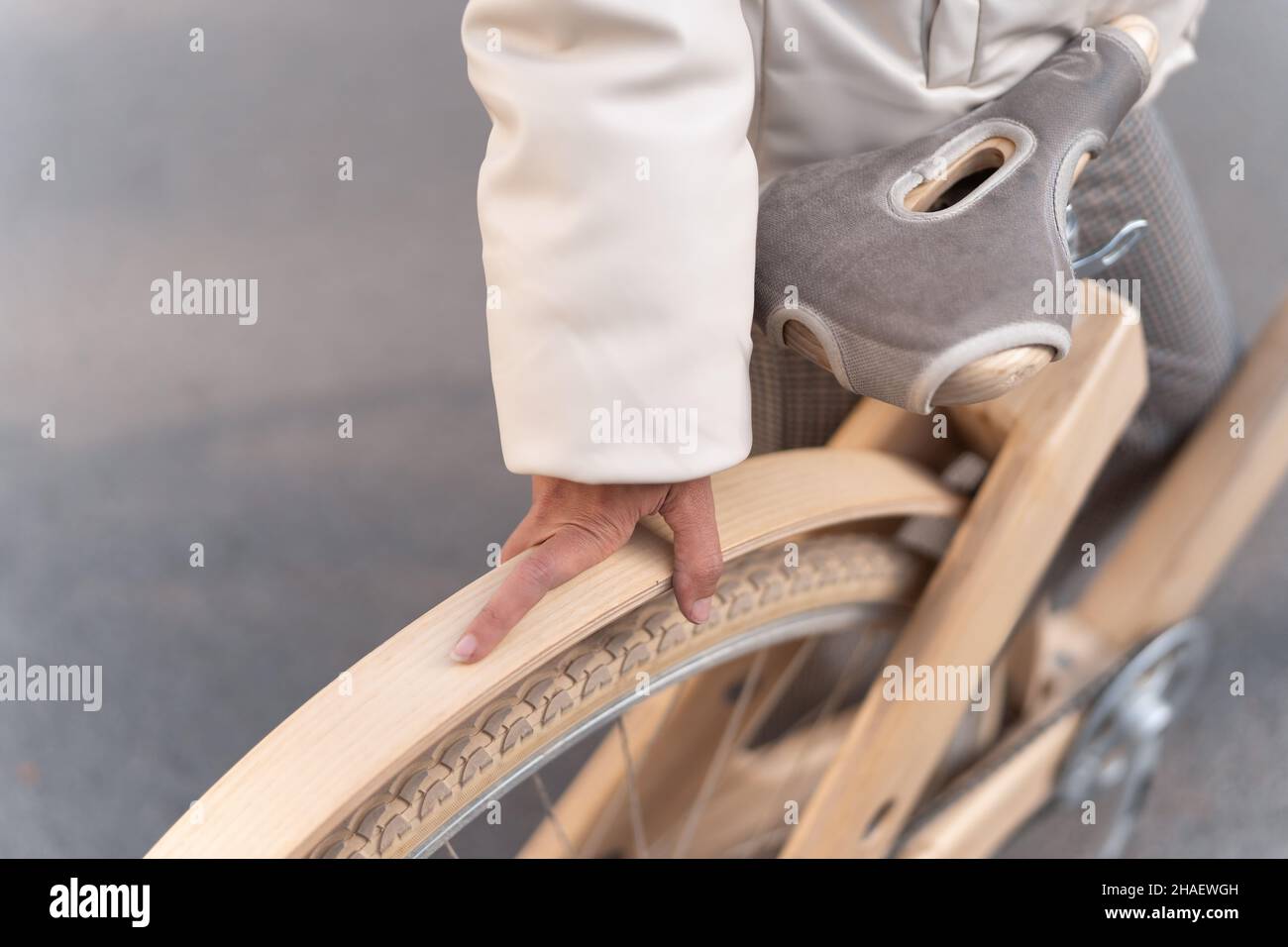 Von oben anonyme Frau in Oberbekleidung berühren Rad von Holz umweltfreundliche Fahrrad, während auf der Straße der Stadt stehen. Stockfoto